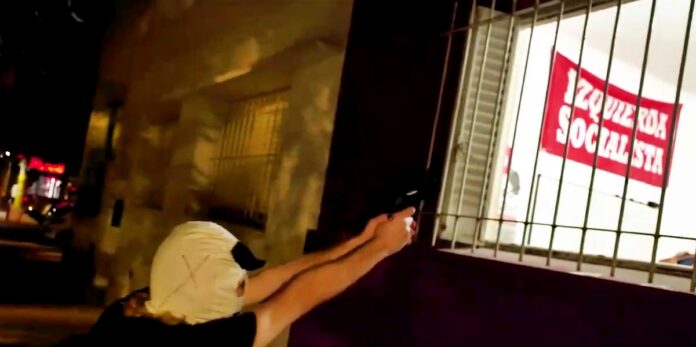 El momento en que el militante encapuchado se filma apuntando hacia el interior del local. (Captura de video)